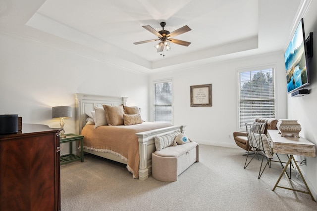 carpeted bedroom featuring a tray ceiling and ceiling fan