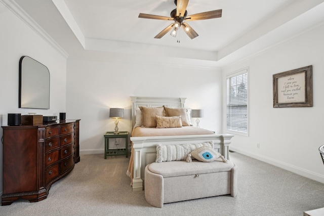 carpeted bedroom with ceiling fan, crown molding, and a tray ceiling