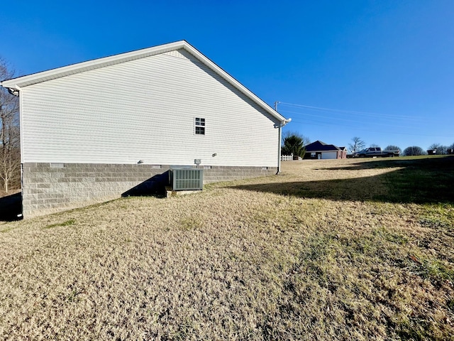 view of side of home featuring central AC unit and a yard