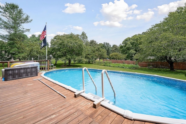 view of pool with a lawn, a trampoline, and a wooden deck