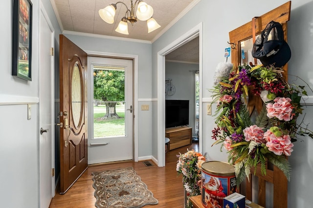 doorway featuring light wood-type flooring, a notable chandelier, and ornamental molding