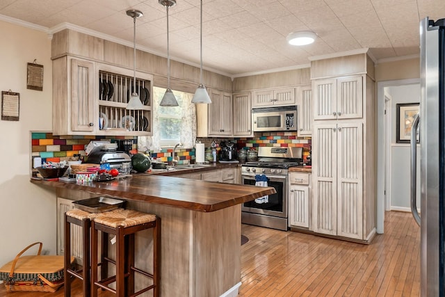 kitchen with wooden counters, stainless steel appliances, kitchen peninsula, and a breakfast bar area