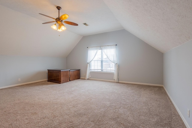 additional living space with lofted ceiling, a textured ceiling, light colored carpet, and ceiling fan