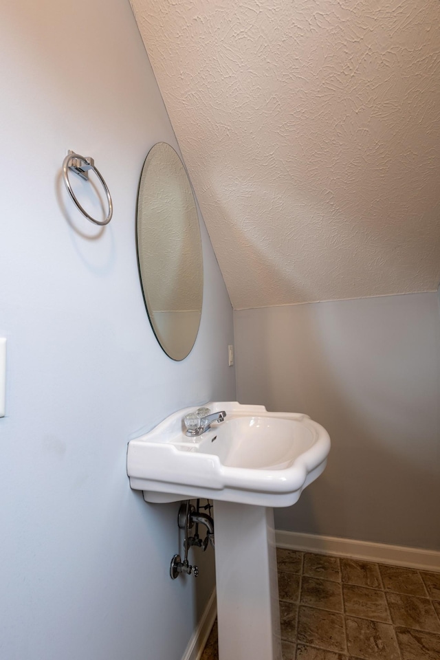 bathroom featuring vaulted ceiling and a textured ceiling