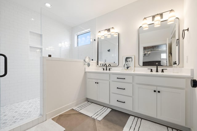 bathroom featuring tile patterned flooring, vanity, and a tile shower