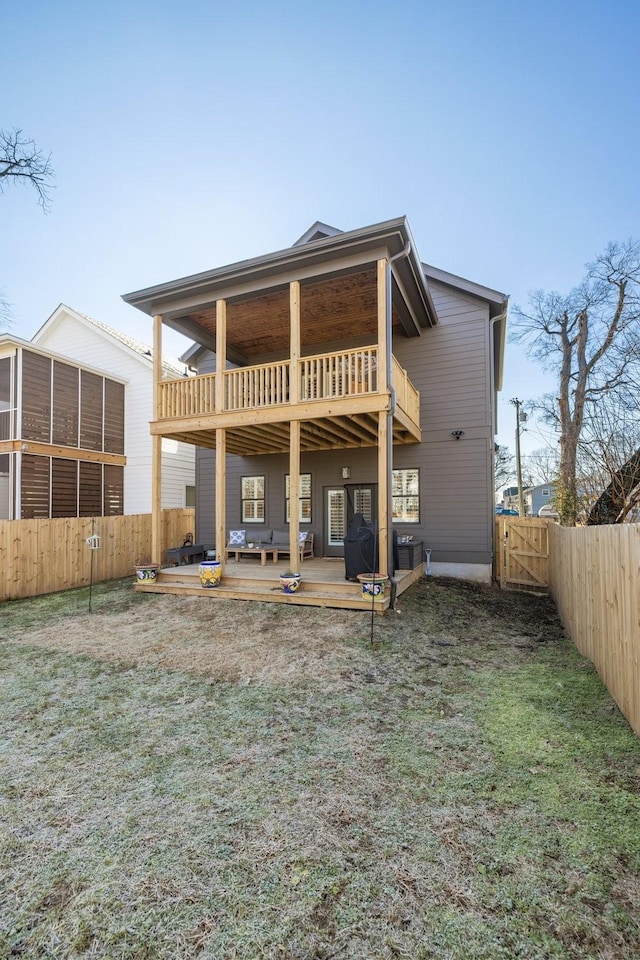 rear view of property with a lawn, a balcony, and a deck