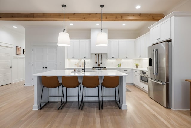 kitchen featuring white cabinetry, a center island with sink, decorative light fixtures, and appliances with stainless steel finishes