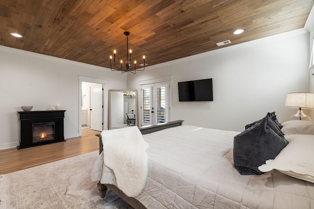 bedroom with french doors, light hardwood / wood-style floors, an inviting chandelier, and access to outside