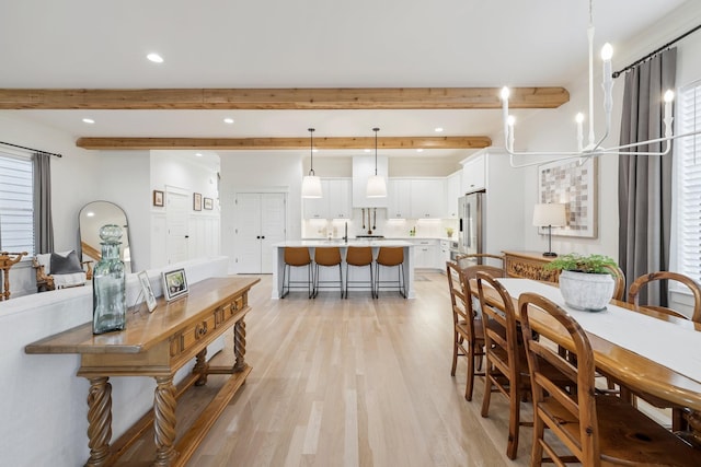 dining room with beamed ceiling, a notable chandelier, and light wood-type flooring