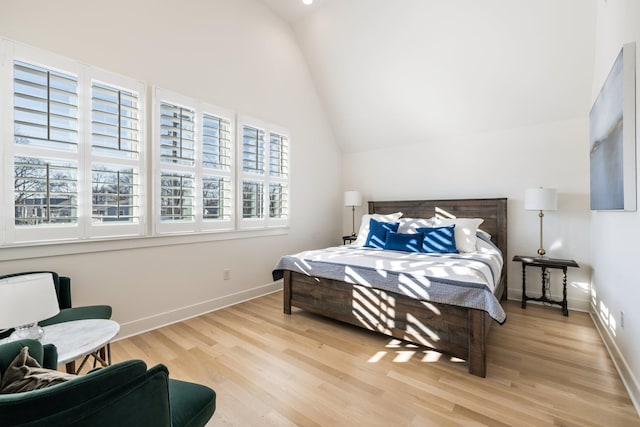 bedroom featuring light hardwood / wood-style floors, lofted ceiling, and multiple windows