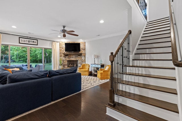 living room with a fireplace, ornamental molding, ceiling fan, and dark wood-type flooring