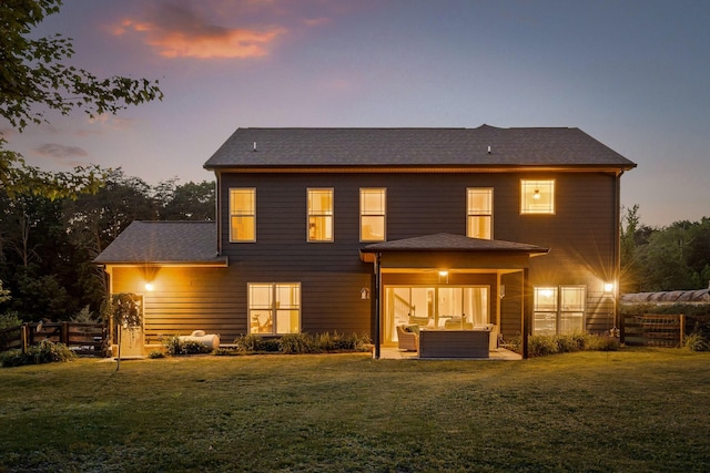 back house at dusk with outdoor lounge area, a patio area, and a yard