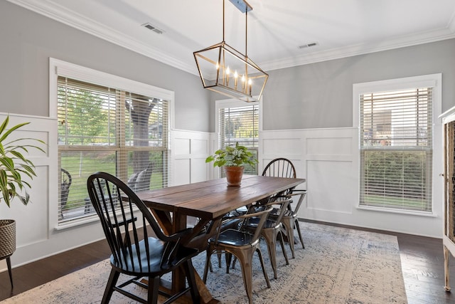 dining space featuring dark wood-type flooring, a chandelier, and ornamental molding