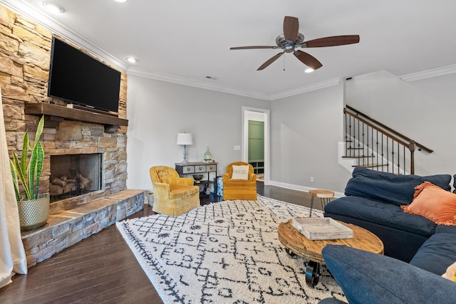 living room with dark hardwood / wood-style floors, a stone fireplace, ceiling fan, and crown molding