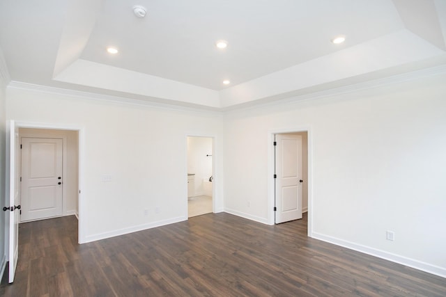 empty room with crown molding, a tray ceiling, and dark hardwood / wood-style floors