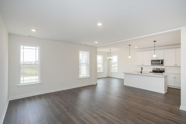 unfurnished living room with sink, a notable chandelier, and dark hardwood / wood-style floors