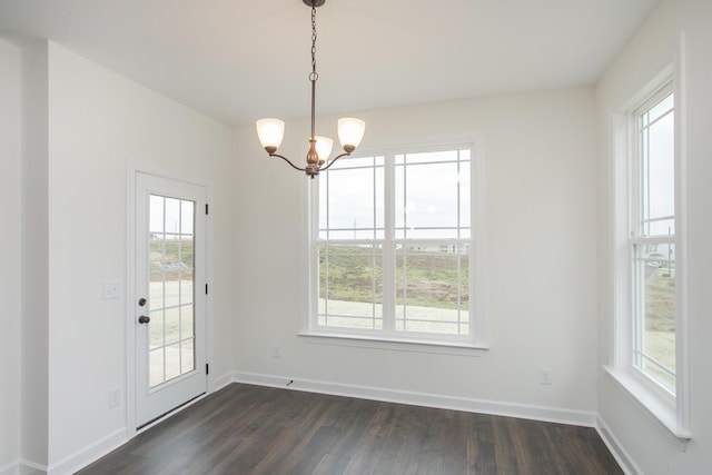 unfurnished dining area featuring a notable chandelier, a wealth of natural light, and dark wood-type flooring