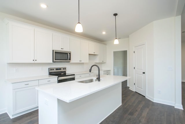 kitchen featuring pendant lighting, stainless steel appliances, sink, and a center island with sink