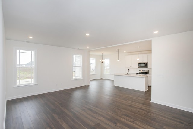 unfurnished living room with sink, dark wood-type flooring, and a chandelier