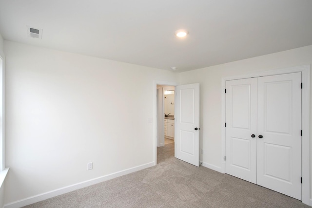 unfurnished bedroom with light carpet and a closet