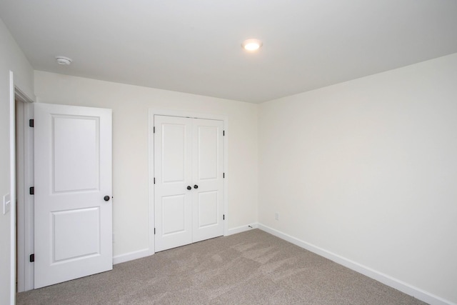 unfurnished bedroom featuring light colored carpet and a closet