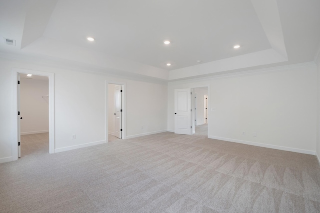 carpeted empty room featuring a tray ceiling and crown molding