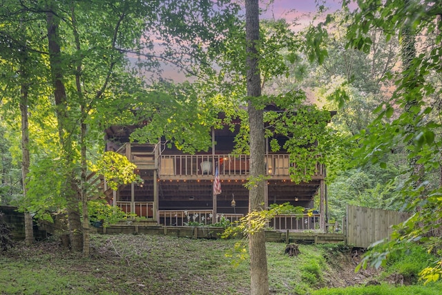 back house at dusk featuring a wooden deck