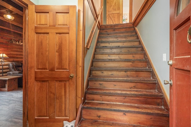 stairway featuring log walls and wood-type flooring