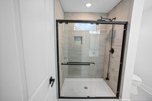 bathroom with toilet and a shower with shower door