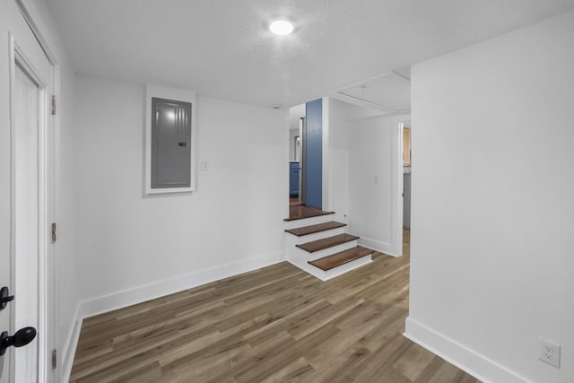 basement featuring dark hardwood / wood-style floors, a textured ceiling, and electric panel