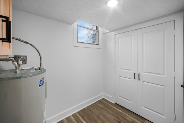 washroom with a textured ceiling, electric water heater, and dark hardwood / wood-style flooring