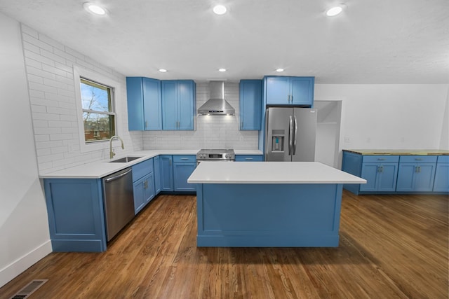 kitchen featuring sink, stainless steel appliances, wall chimney range hood, dark hardwood / wood-style floors, and decorative backsplash