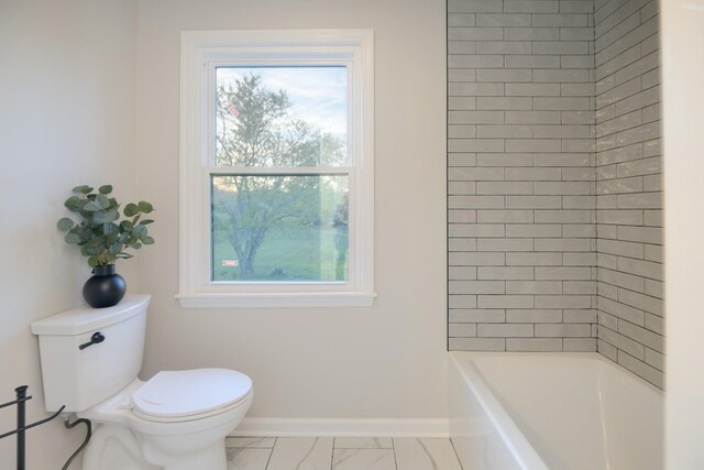 bathroom featuring tiled shower / bath combo and toilet