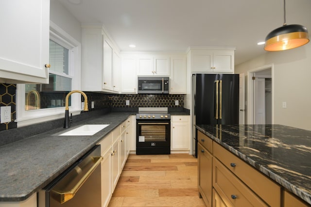 kitchen with pendant lighting, white cabinets, sink, light wood-type flooring, and appliances with stainless steel finishes