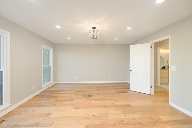 spare room featuring light wood-type flooring and a notable chandelier