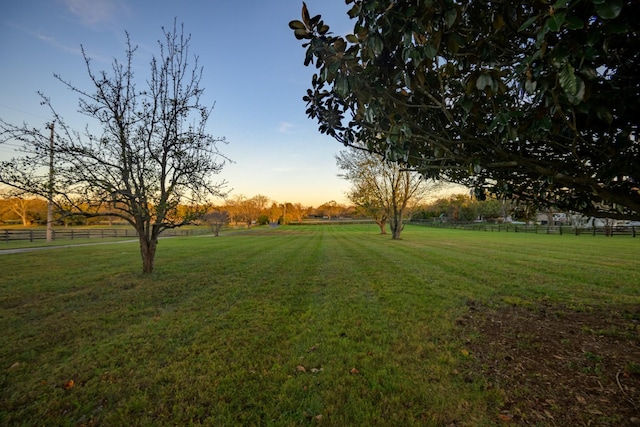 yard at dusk featuring a rural view