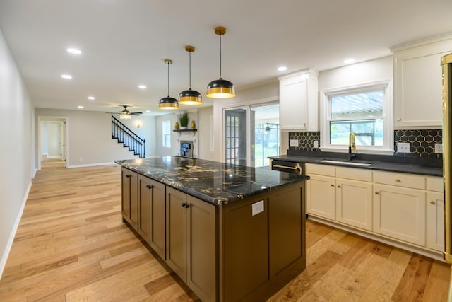 kitchen featuring backsplash, ceiling fan, sink, decorative light fixtures, and white cabinets