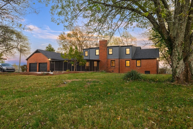 back house at dusk featuring a lawn, a sunroom, and a garage