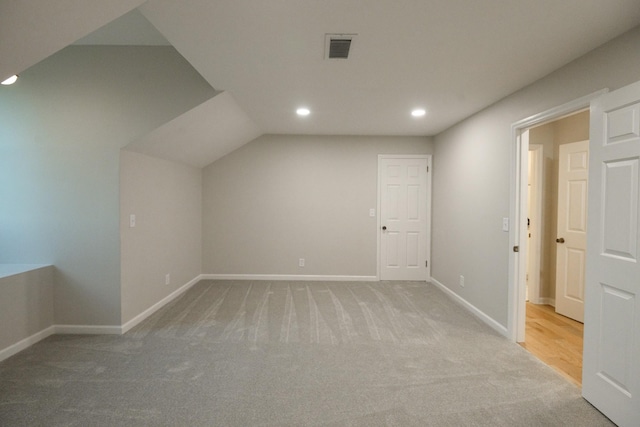 additional living space with light carpet and vaulted ceiling