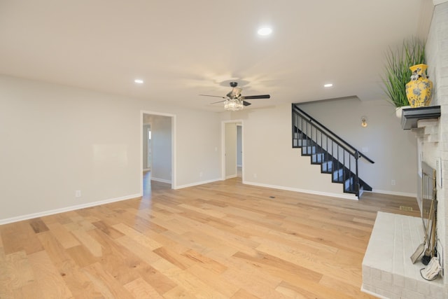 unfurnished living room featuring a fireplace, light hardwood / wood-style flooring, and ceiling fan