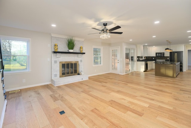 unfurnished living room with a fireplace, light wood-type flooring, and ceiling fan