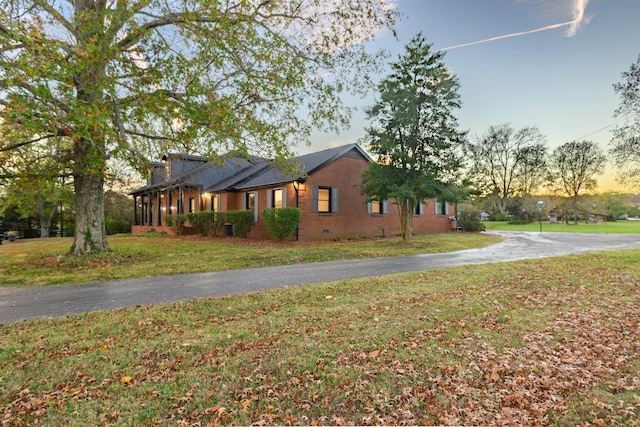 property exterior at dusk featuring a yard