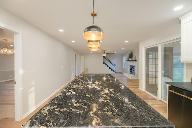 kitchen featuring dishwashing machine, decorative light fixtures, white cabinetry, and dark stone countertops