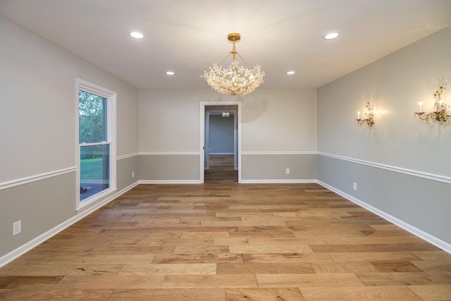 unfurnished room with light hardwood / wood-style floors and a chandelier