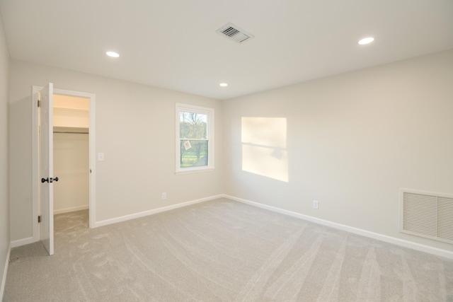 unfurnished bedroom featuring a walk in closet, light carpet, and a closet