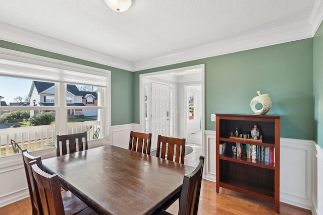 dining area with light hardwood / wood-style floors, a healthy amount of sunlight, and ornamental molding