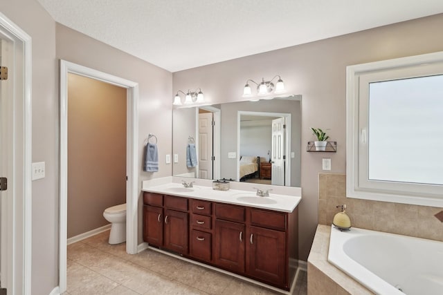 bathroom featuring tile patterned floors, vanity, toilet, and tiled tub