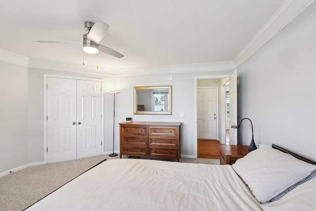 carpeted bedroom featuring ceiling fan, crown molding, and a closet