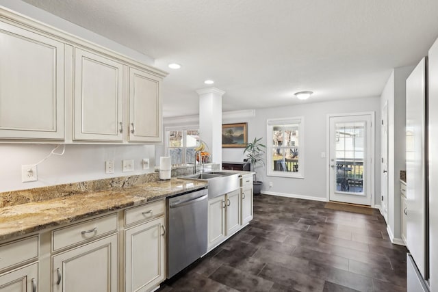 kitchen featuring stainless steel dishwasher, a healthy amount of sunlight, light stone countertops, and cream cabinetry