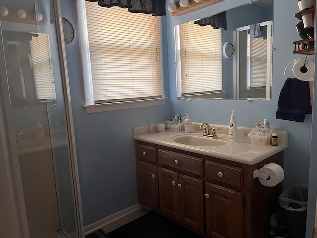 bathroom with vanity, a shower with shower door, and a healthy amount of sunlight